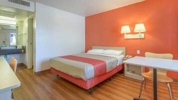 Ein Hotelzimmer mit Bett, Schreibtisch, Stuhl und angrenzendem Badezimmer.