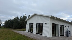 Ein modernes Haus mit Satteldach, großen Schiebeglastüren und einer überdachten Veranda.