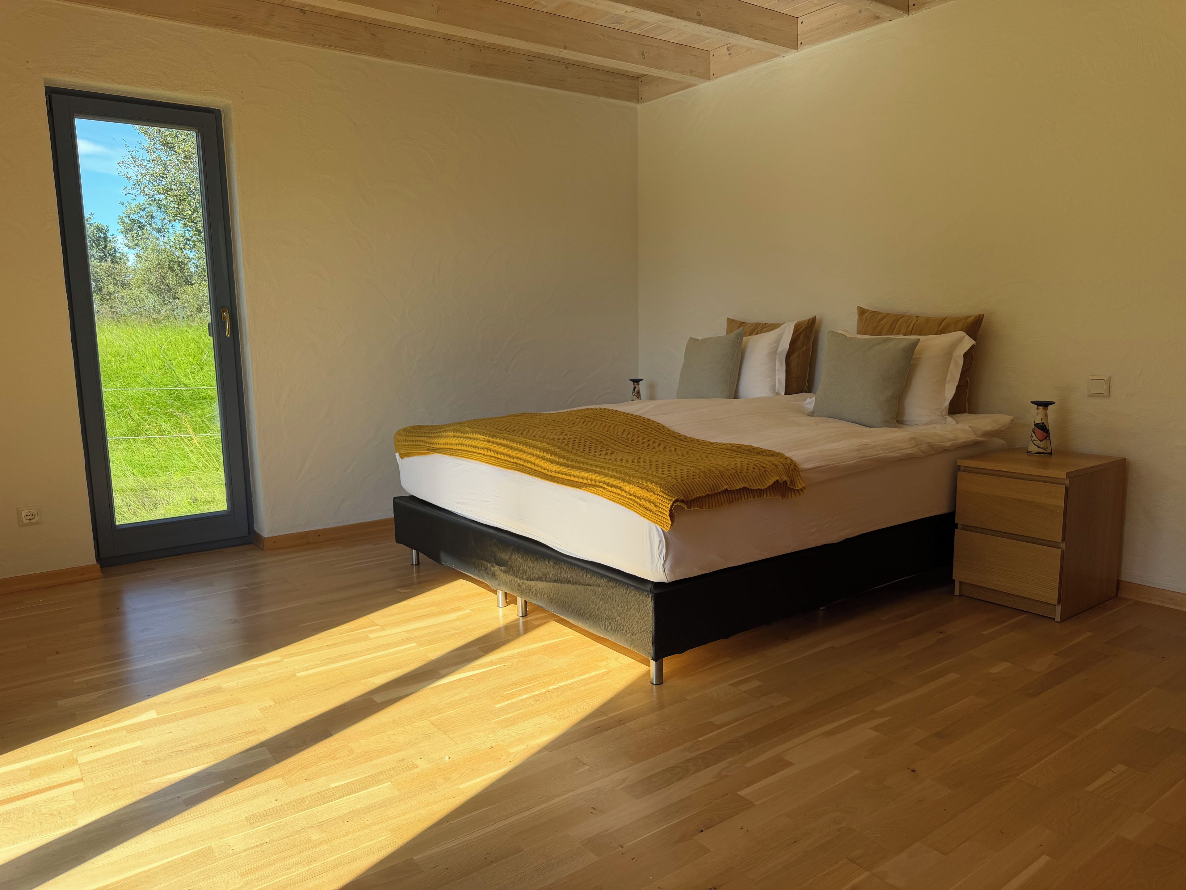 Een slaapkamer met een bed, een nachtkastje en uitzicht door een deur.