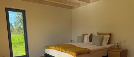 A bedroom with a bed, a nightstand, and a view through a door.