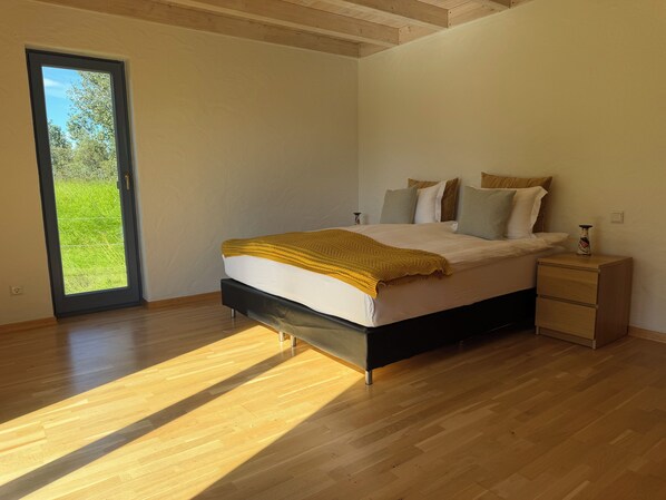 A bedroom with a bed, a nightstand, and a view through a door.