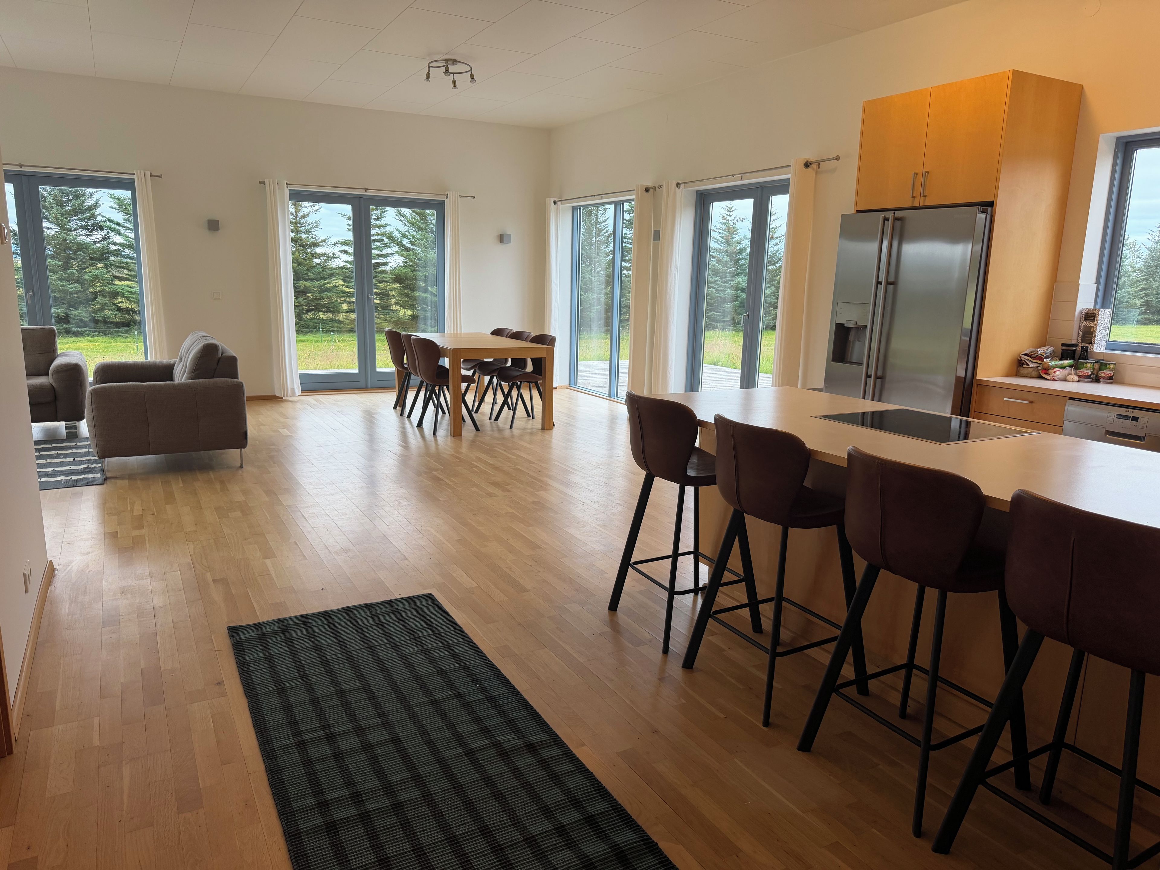Una cocina moderna con una isla grande, taburetes de bar y un comedor con mesa y sillas.