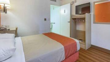 A hotel room with a bed, a desk with a telephone, a wardrobe, and a television.