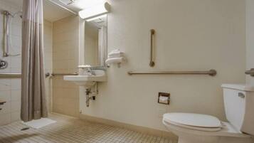 A standard bathroom with a shower, sink, toilet, and grab bars.
