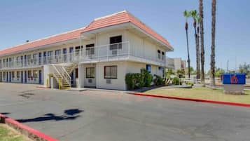 A two-story motel with a red roof, a covered parking area, and a sign indicating the number 6.