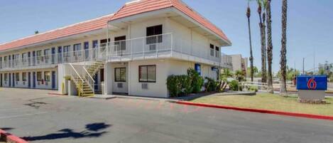 A two-story motel with a red roof, a covered parking area, and a sign indicating the number 6.
