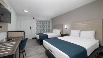 A hotel room with two beds, a desk, and a chair.