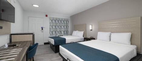 A hotel room with two beds, a desk, and a chair.