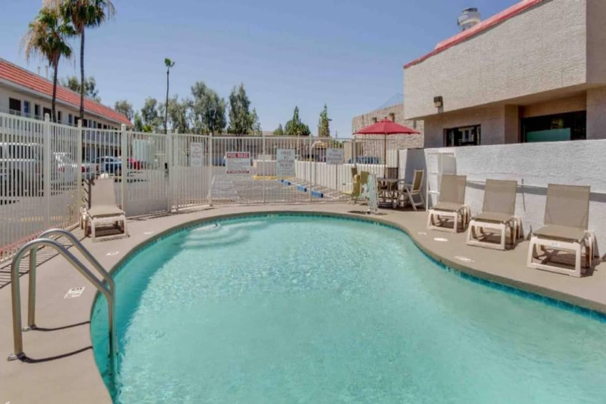 A swimming pool with lounge chairs and a fence.