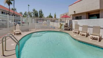A swimming pool with lounge chairs and a fence.