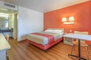 Una habitación de hotel con cama, escritorio, silla y baño a la vista.