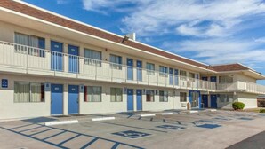 Um motel com várias divisas, um estacionamento com vagas acessíveis para pessoas com deficiência e céu claro.