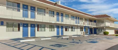 Een motel met meerdere kamers, een parkeerplaats met parkeerplaatsen voor mindervaliden en een heldere lucht.