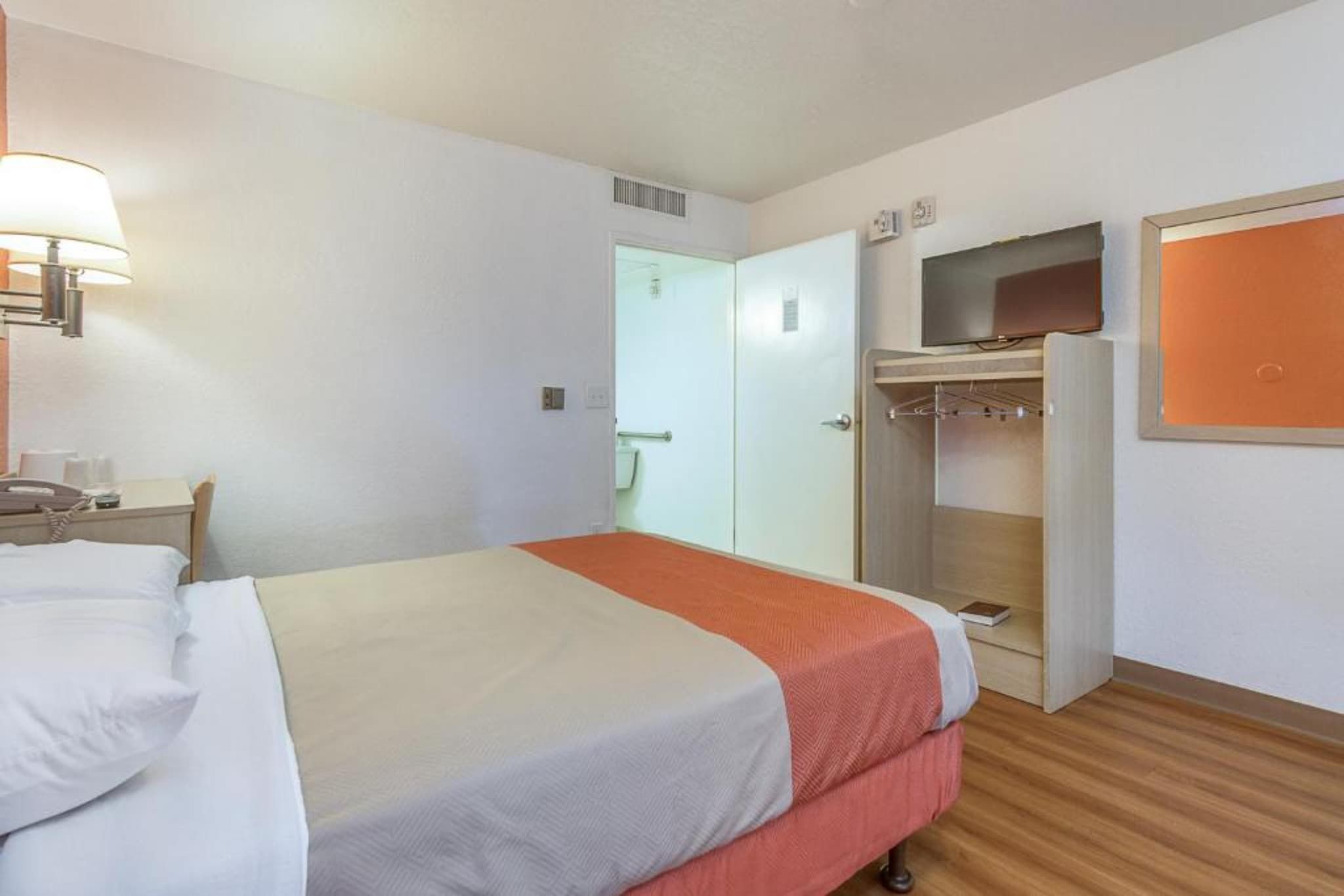 Une chambre d’hôtel comprenant un lit, un bureau avec une lampe, une armoire et un téléviseur.