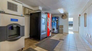 Un couloir avec des distributeurs automatiques, un point d’eau et un réfrigérateur rempli de Coca-Cola.