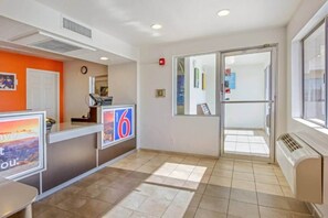A hotel reception area with a reception desk, a clock, and a door leading to another room. - 2 Full Beds | Phoenix (Phoenix)