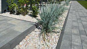 A modern building with a pathway lined with plants and a gravel bed. - Baltic Atelier (Grzybowo)