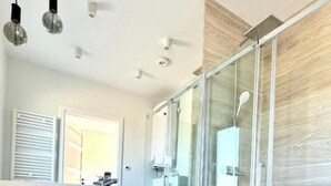 A modern bathroom with a glass shower enclosure, a wooden vanity with a white sink, and a mirror above it. - Baltic Atelier (Grzybowo)