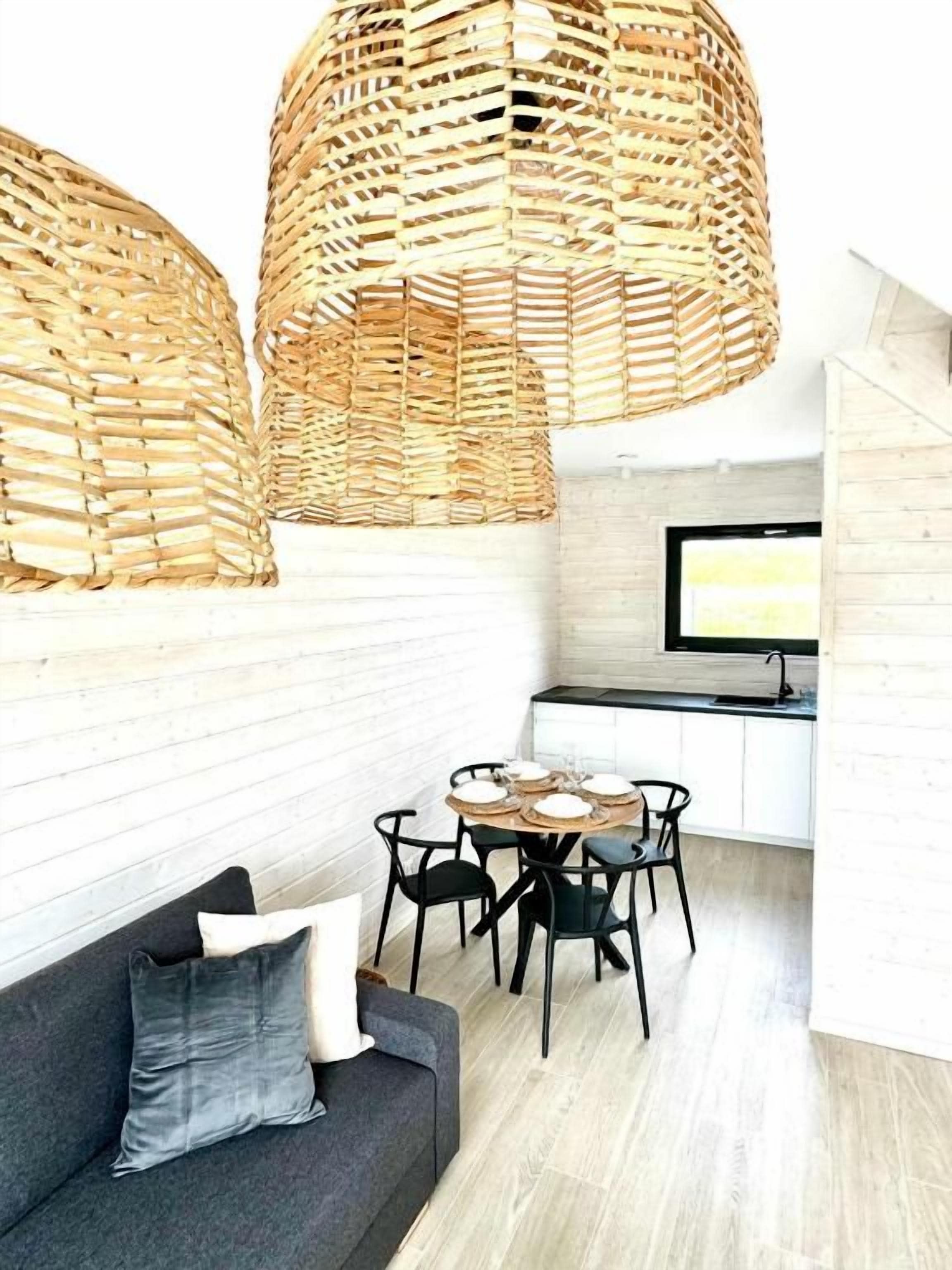 Un intérieur moderne avec un canapé, une table à manger, des chaises et des lampes en osier.