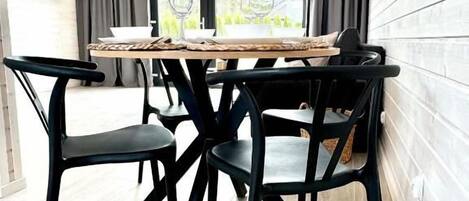 A dining area with a round table, black chairs, and a woven light fixture.