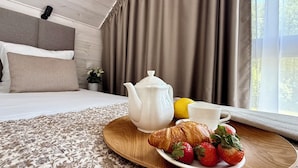 A bedroom with a bed, a bedside table with a teapot, a plate of strawberries, and a croissant. - Baltic Atelier (Grzybowo)