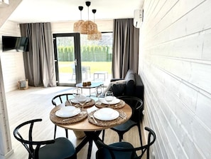 Un comedor con una mesa redonda para cuatro personas, un sofá y un televisor montado en la pared.