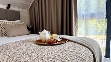 A neatly made bed with a floral-patterned bedspread, a tray with a teapot, a cup, and a croissant with strawberries.
