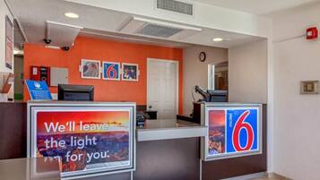 A hotel reception area with a counter, a sign indicating the number 6, and a sign with a sunset image and text.