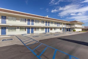 Ein Motel mit Parkplatz, gekennzeichnet für Menschen mit Behinderung, mehreren Zimmern und blauem Himmel.