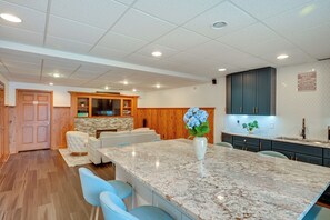 A modern kitchen with a marble island, wooden cabinets, and a stone backsplash. - St Joseph River Retreat w/ Private Pool (Mishawaka)