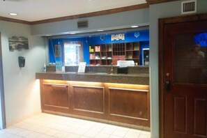 Una taquilla de recepció amb un cartell blau, un taulell de fusta i un paviment de rajoles.