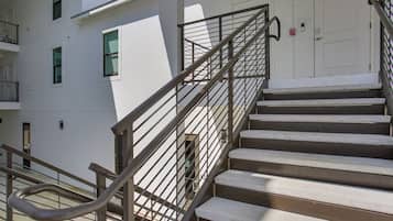 Escadas externas com grades de metal que levam à entrada de um edifício.