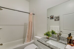 A bathroom with a bathtub, toilet, sink, and a mirror. - Stylish Condo: Walk to Caloosahatchee River (LaBelle)