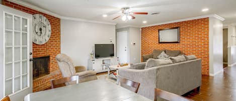 A living room with a fireplace, a dining area with a table and chairs, a sofa, and a television.