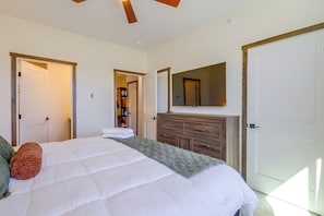 Ein Schlafzimmer mit einem großen Bett, einem Schminktisch, einem Spiegel und zwei Türen.