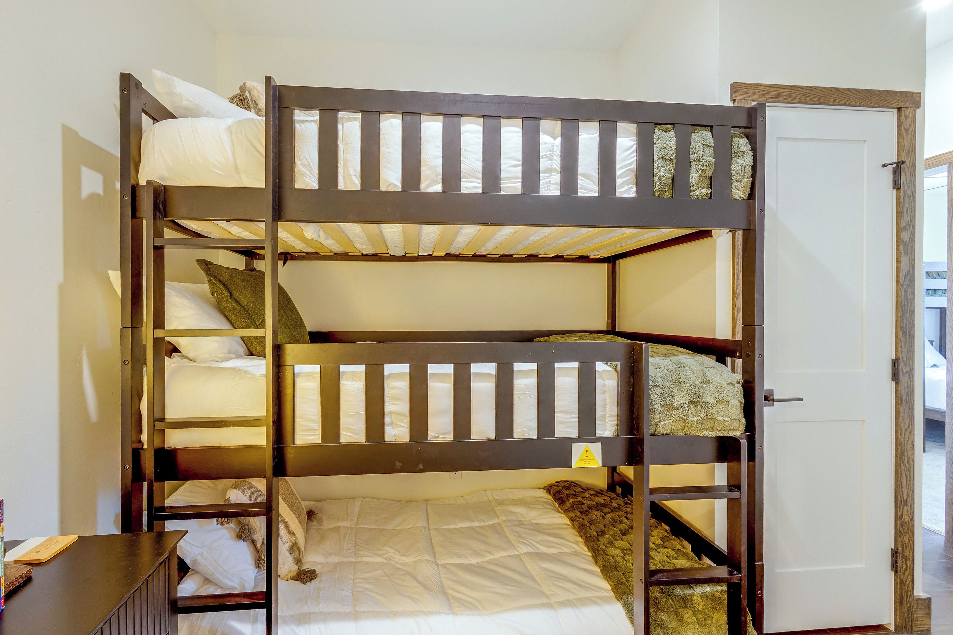 A bunk bed room with a door and a small table.