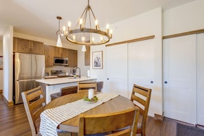 Une cuisine moderne avec des meubles en bois, des appareils électroménagers en acier inoxydable et un lustre.
