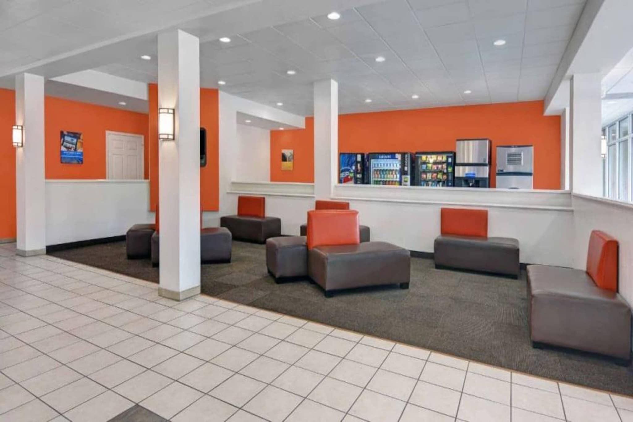 A lobby with multiple seating areas, a vending machine, and a window with a view.