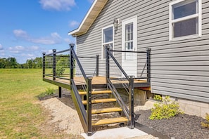 A house with a wooden deck and metal railing leading to a set of stairs. - Fire Pit, Deck, Yard! Home Near Canadian Lakes (Mecosta)