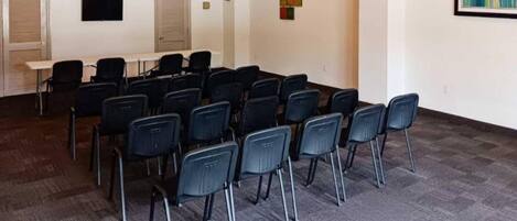 Un salón de conferencias con filas de sillas, una pizarra y una puerta con ventanal.