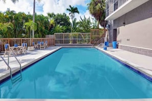 A swimming pool with a wooden deck, lounge chairs, and a fence. - 2 Queen Beds|Premium| Micfridge (Cutler Bay)