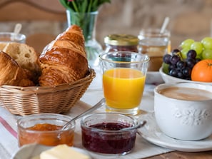 Ein Frühstückstisch mit Brot, Obst, Marmelade und einer Tasse Kaffee.