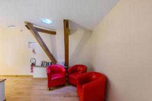 Ein Zimmer mit Holzbalken, einem Feuerlöscher und roten Stühlen.