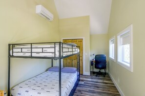 Et værelse med køjeseng, skrivebord, stol, et vindue og en aircondition.