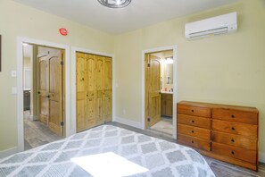 Ein Schlafzimmer mit Bett, Kommode, Kleiderschrank und Klimaanlage.