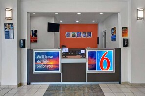 Een hotel receptie met een balie, computers en een groot bord met het nummer 6.