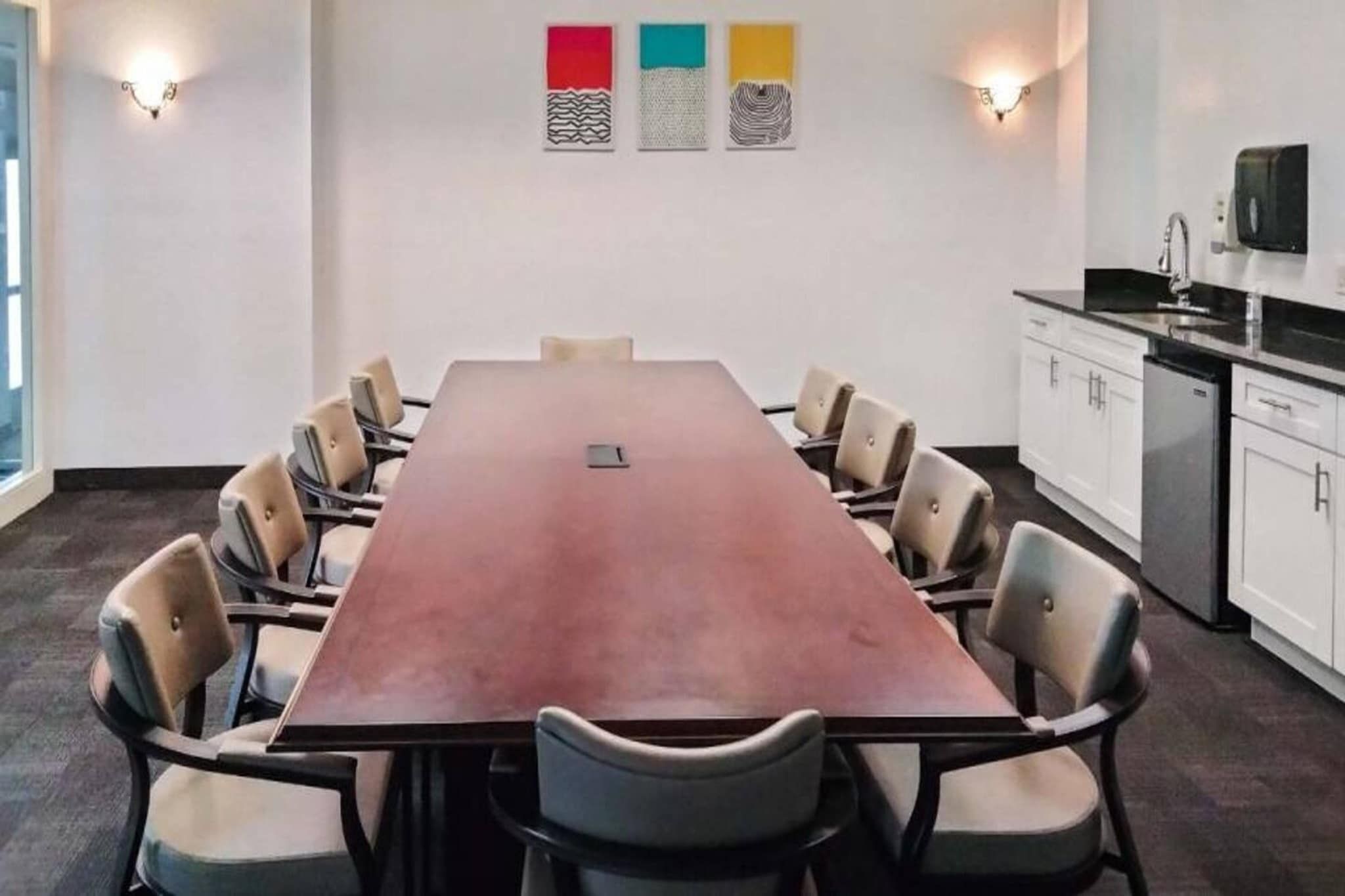 Une salle de conférence équipée d’une longue table, de chaises et d’un coin cuisine.