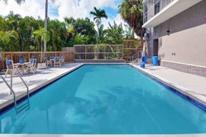 A swimming pool with a wooden deck, lounge chairs, and a fence. - 1 King Bed|Premium| Micfridge (Cutler Bay)