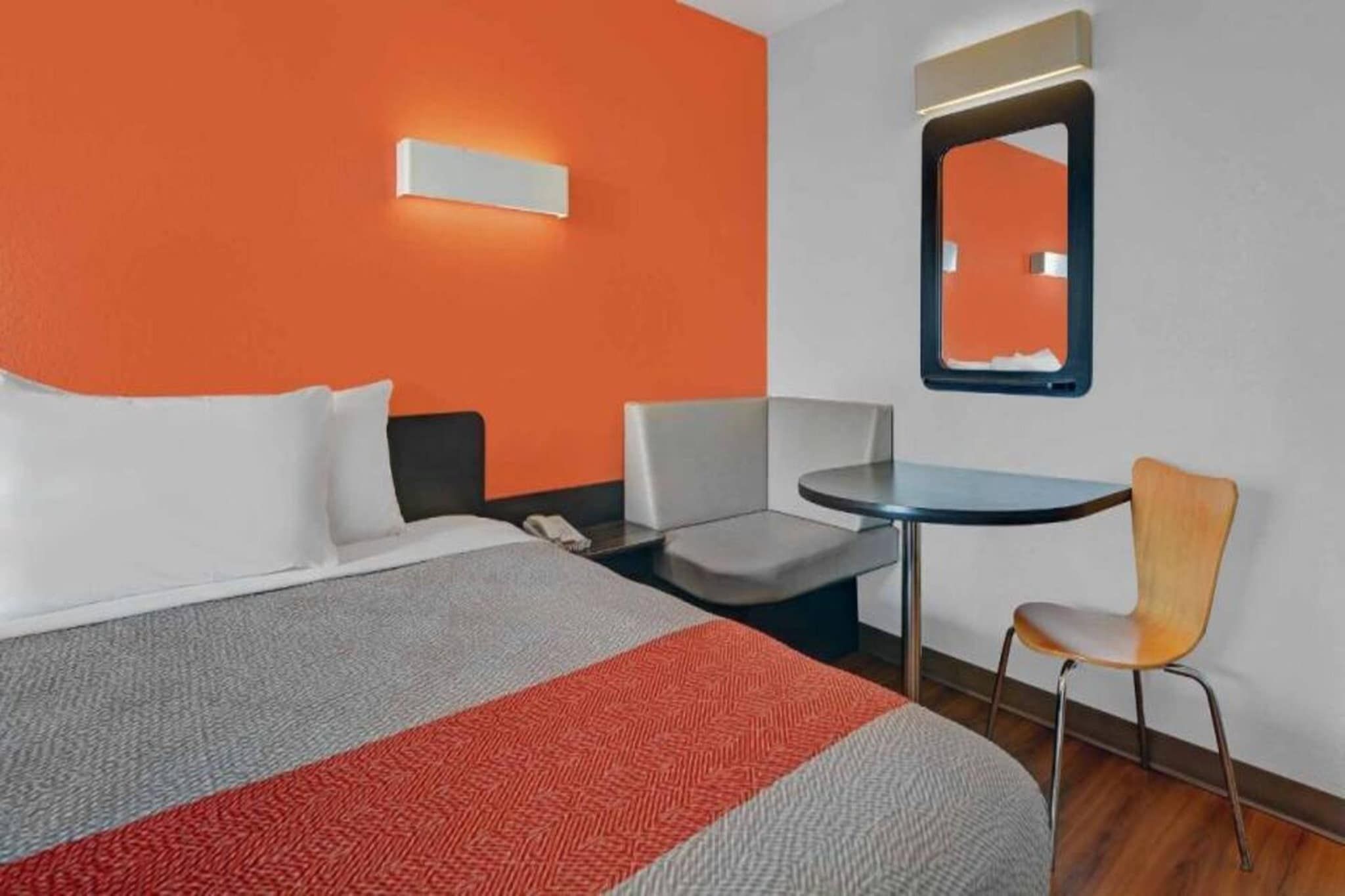 Une chambre d’hôtel avec un lit, un bureau, une chaise et un miroir.