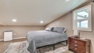 Une chambre à coucher avec un lit, une table de chevet, une lampe, un radiateur et une fenêtre.